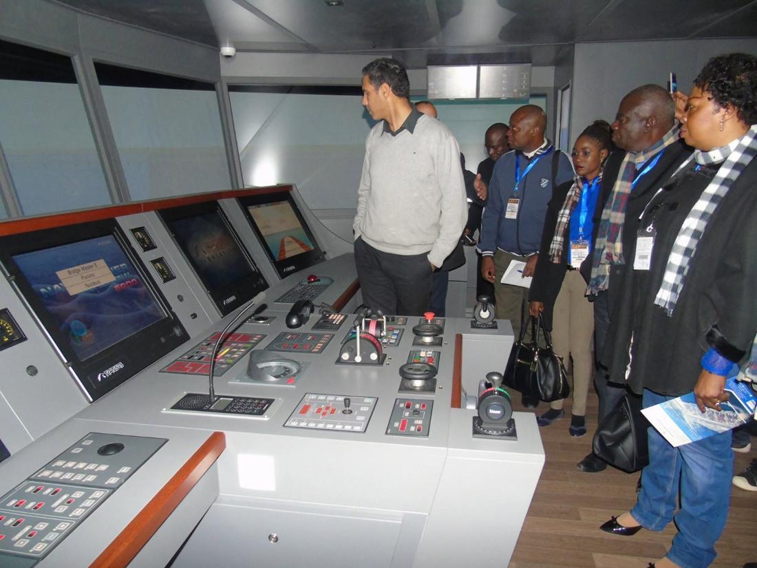 Participants devant un simulateur de conduite de navire